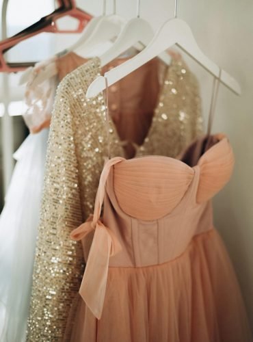 Peach and sequin dresses hanging elegantly on coathangers, perfect for fashion inspiration.