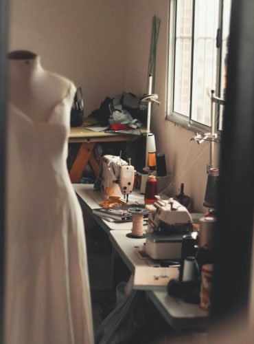 A warm, inviting home sewing room with a dress form and sewing machines at work.